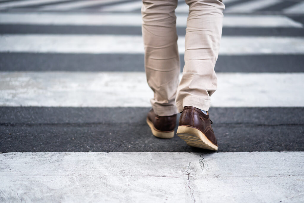 close up legs of man walking cross the street in city